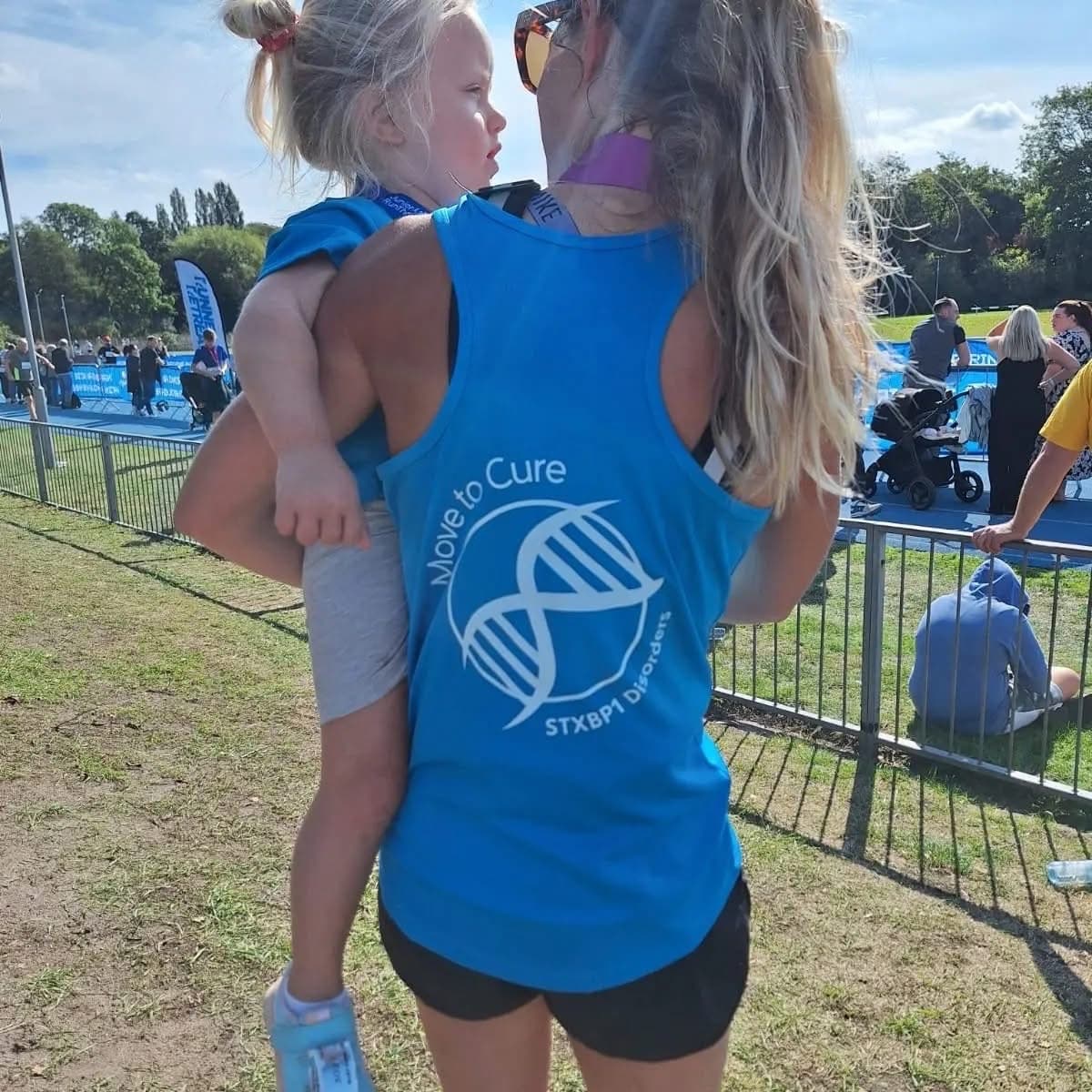 A supporter carrying a child at a Move to Cure fundraising event